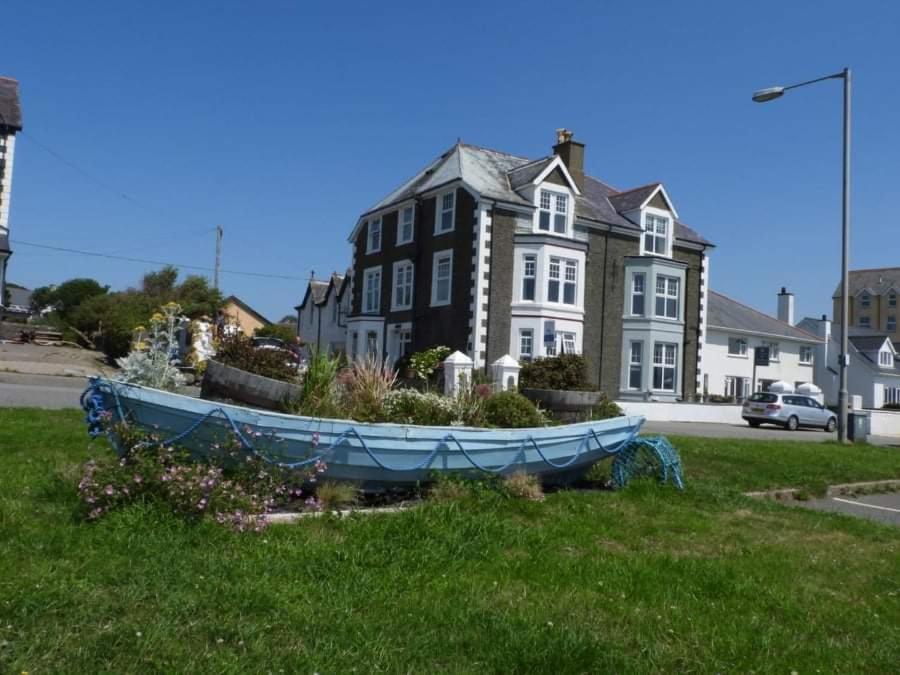 a boat sitting in the grass in front of a house at Craig-y-Mor in Criccieth
