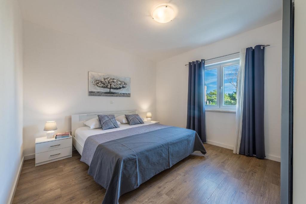 a bedroom with a bed with blue sheets and a window at Holiday Home Bajlo apartment with three bedrooms in Zadar