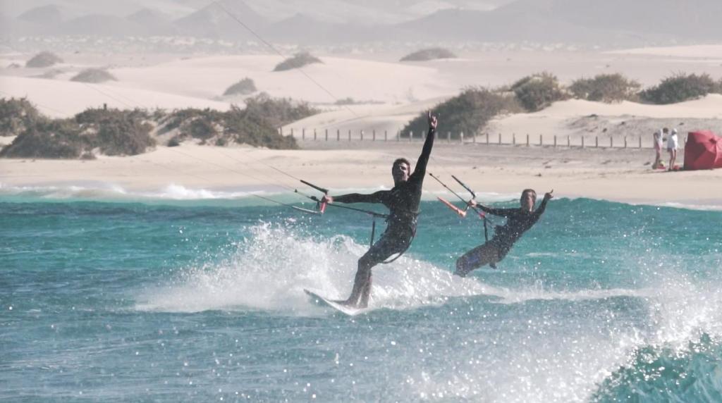 two people on surfboards riding a wave in the ocean at Surfescape Fuerteventura in Lajares