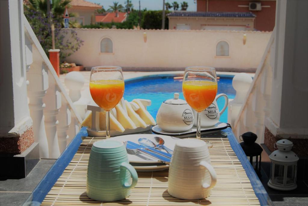 two glasses of orange juice on a table next to a swimming pool at Casa de Limón in Ciudad Quesada