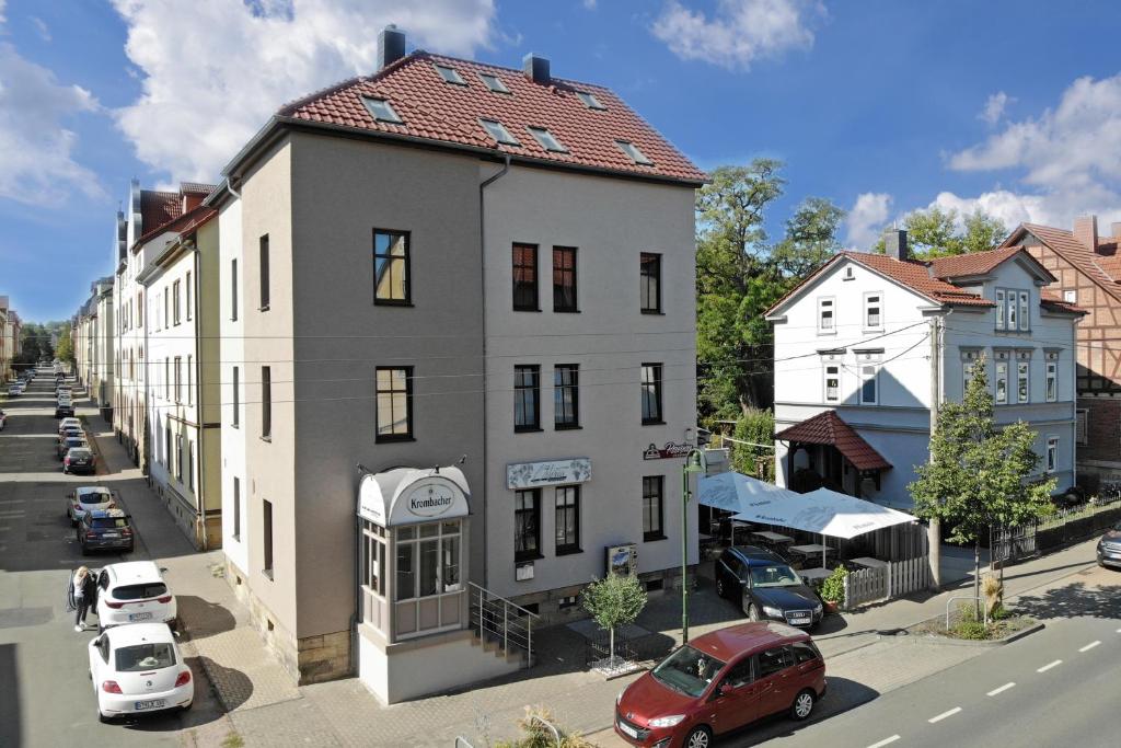 un grand bâtiment blanc avec un toit rouge dans une rue dans l'établissement Weisser Brunnen, à Gotha