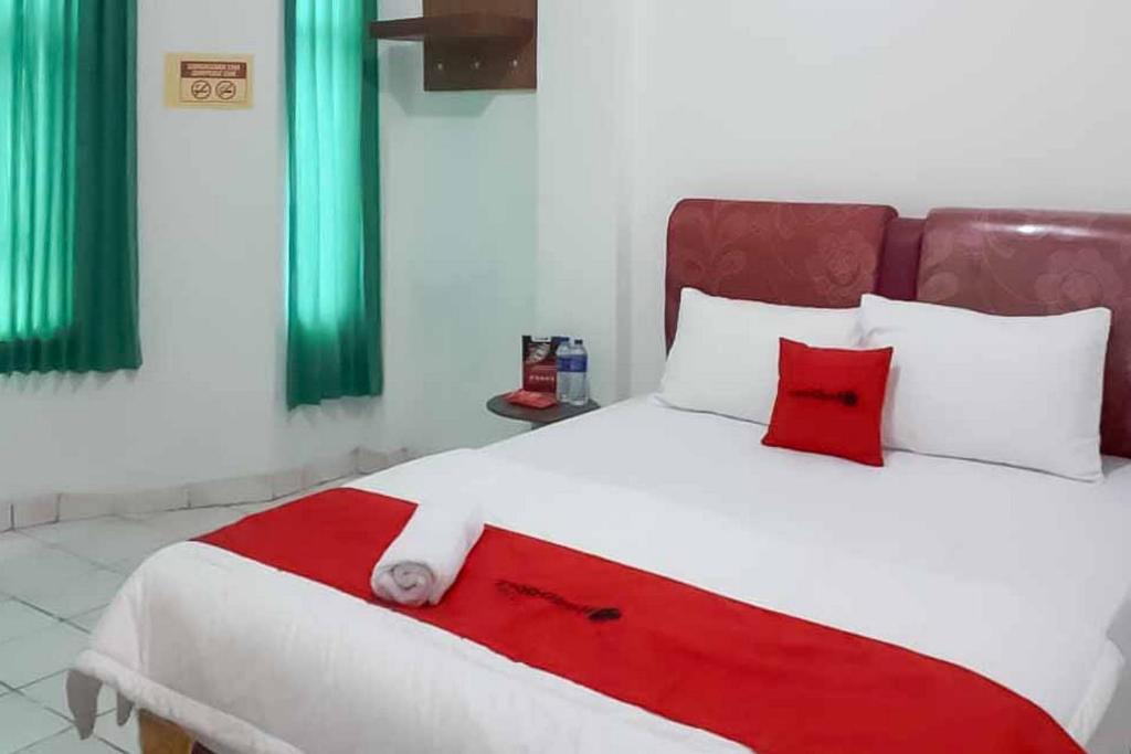 a bedroom with a large bed with red and white pillows at RedDoorz near Lampung Walk 2 in Tanjungkarang