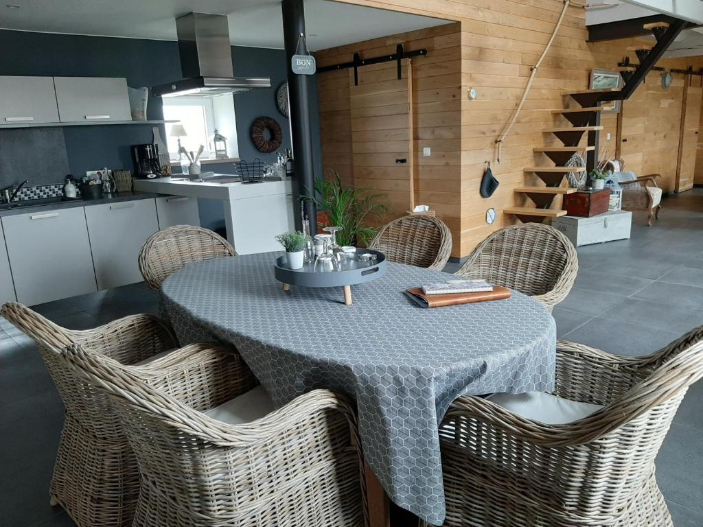 a dining room table with wicker chairs and a kitchen at La petite Juliette in Leuze-en-Hainaut