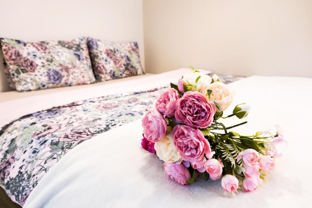 a bouquet of pink flowers sitting on a bed at Шале Тюленя - Шереметьево in Moscow