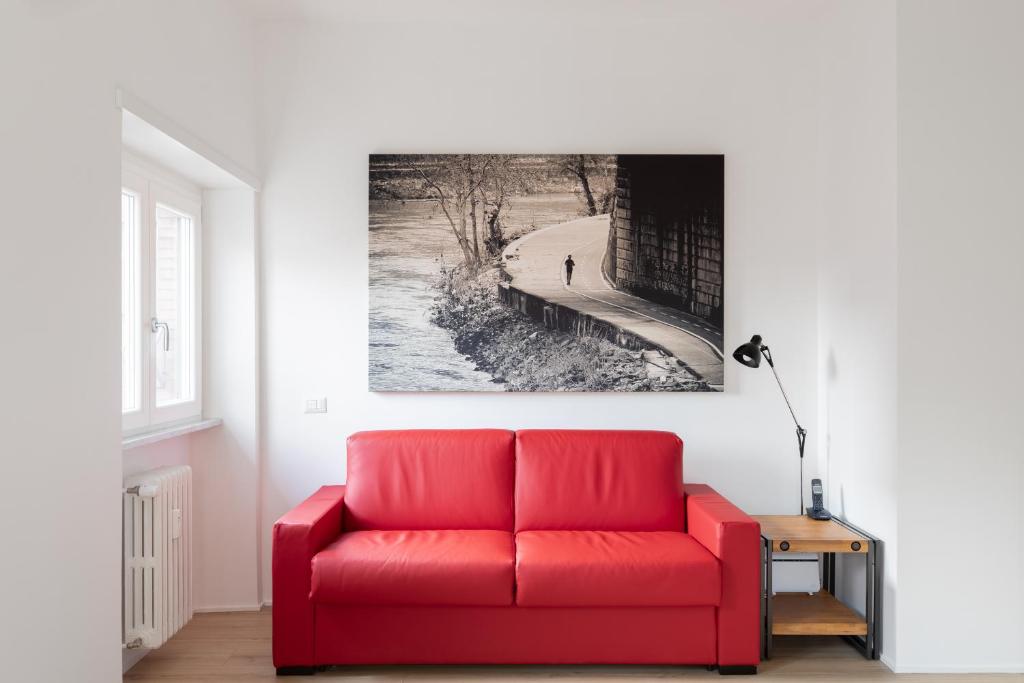 um sofá vermelho numa sala de estar com uma fotografia na parede em Roman Residenza em Roma