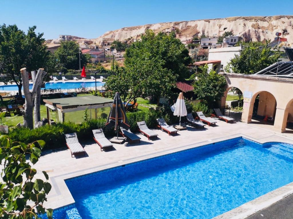 a pool with chairs and umbrellas next to a resort at Melis Cave Hotel in Urgup