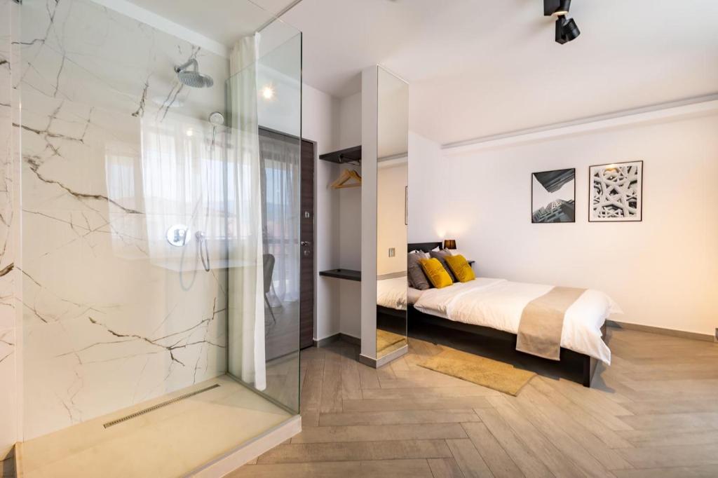 a bedroom with a bed and a glass shower at Urbio Private Suites in Cluj-Napoca