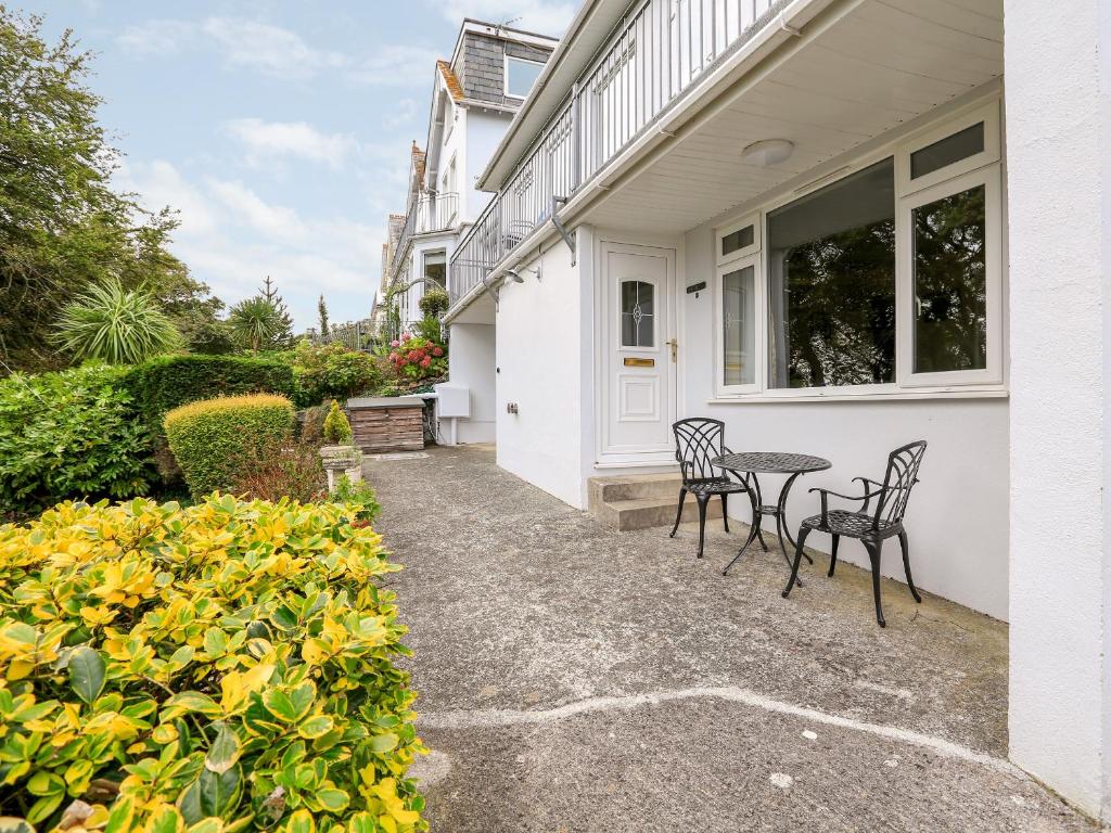 a patio with two chairs and a table on the side of a house at Sunrise, 8 Melbury in Salcombe