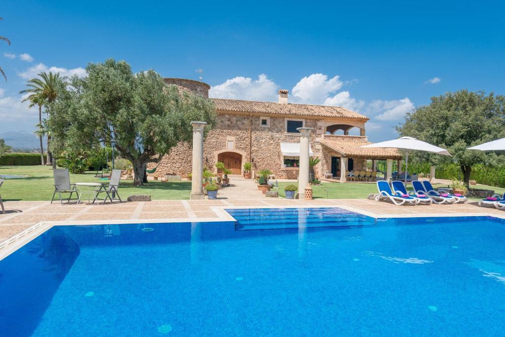 a villa with a swimming pool in front of a house at Can Colis in Sa Pobla