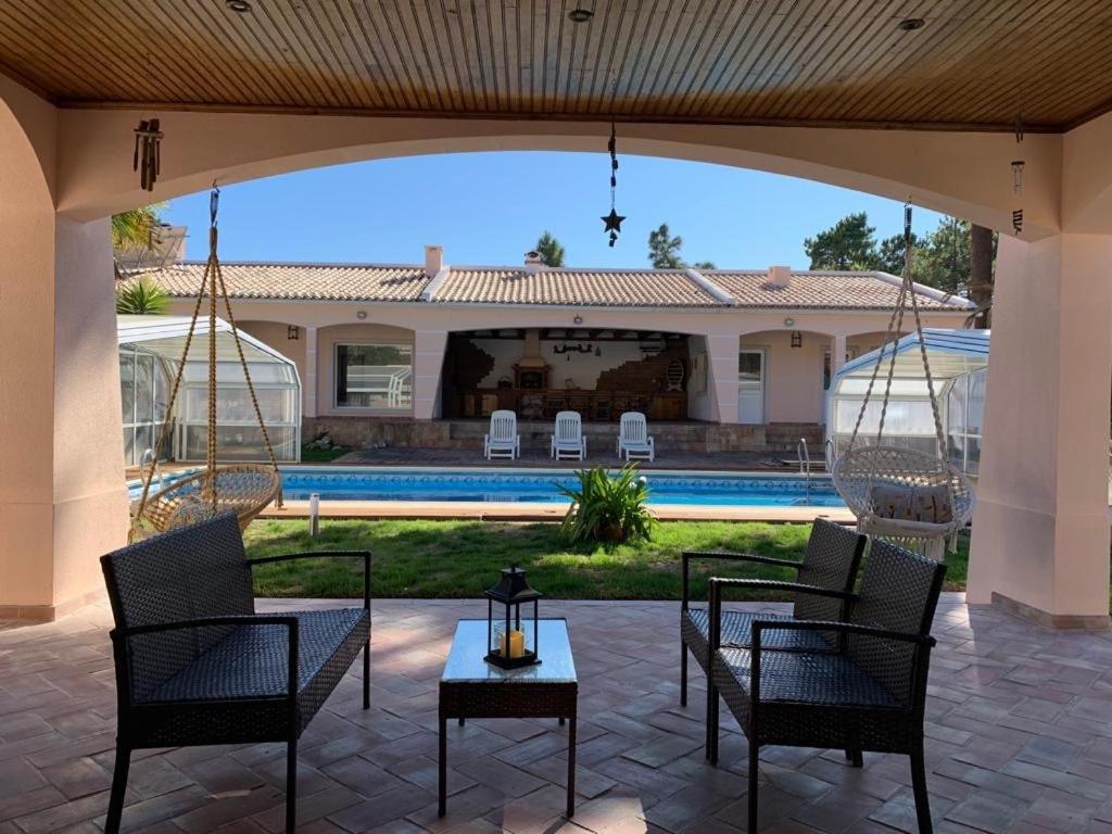 patio z krzesłami i stołem oraz basenem w obiekcie Moradia Pinhal da Telha w mieście Corroios