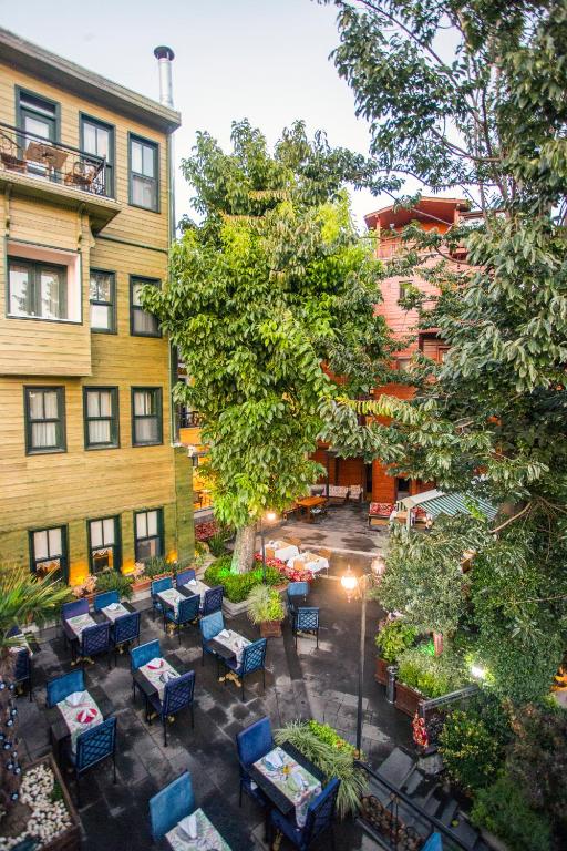 un patio al aire libre con mesas, sillas y un árbol en Garden House Hotel - Special Class, en Estambul