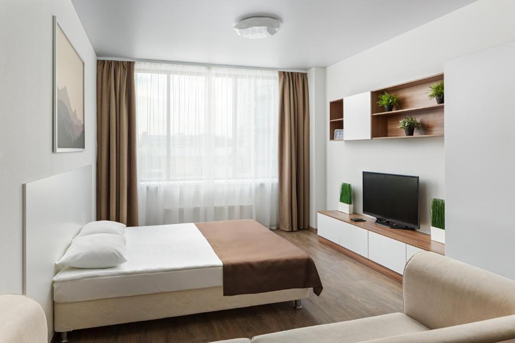 a white bedroom with a bed and a tv at RADIUS Central House in Yekaterinburg