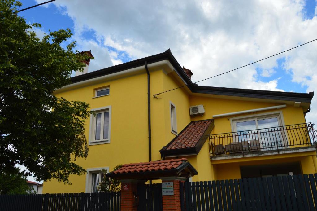 ein gelbes Haus mit einem Zaun davor in der Unterkunft Apartment Kancler in Nova Gorica