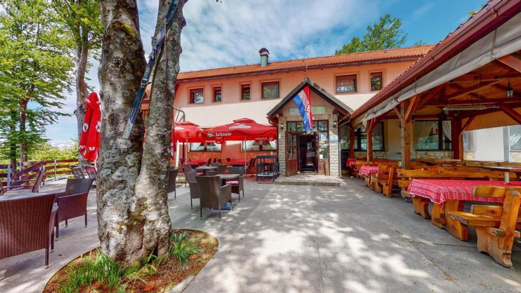 eine Terrasse mit Tischen und Stühlen und ein Gebäude in der Unterkunft Planinarski Centar Petehovac in Delnice