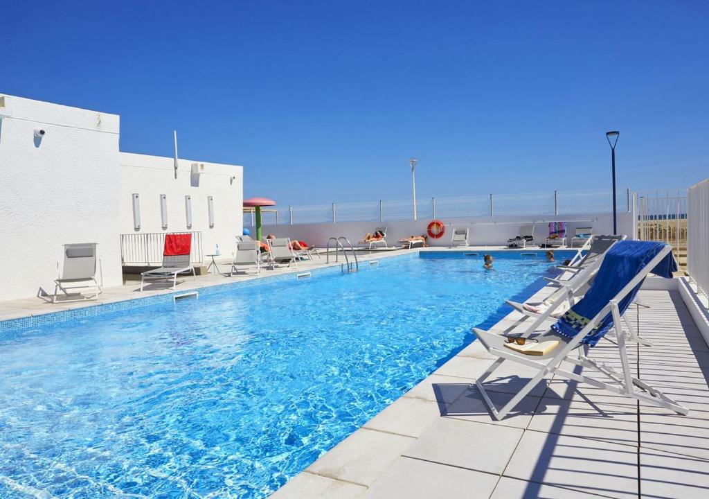 a large swimming pool with chairs and a slide at Résidence Néméa Les Carrats - Port Leucate in Port Leucate