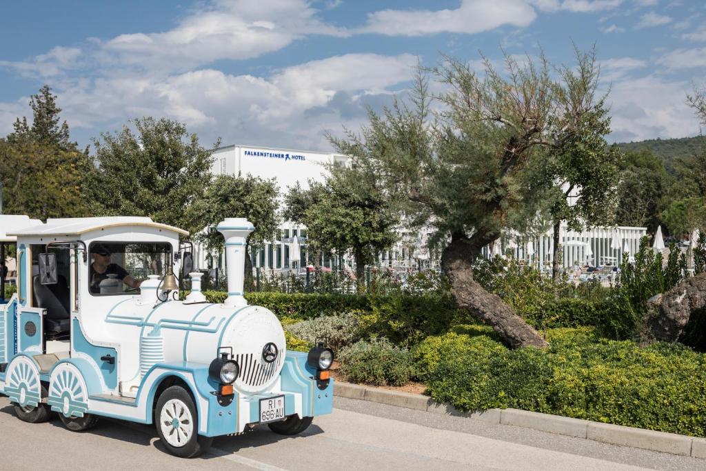 a small blue and white train driving down a street at Falkensteiner Hotel Park Punat in Punat