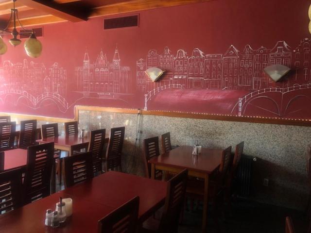 a restaurant with tables and chairs and a red wall at Delta Hotel City Center in Amsterdam