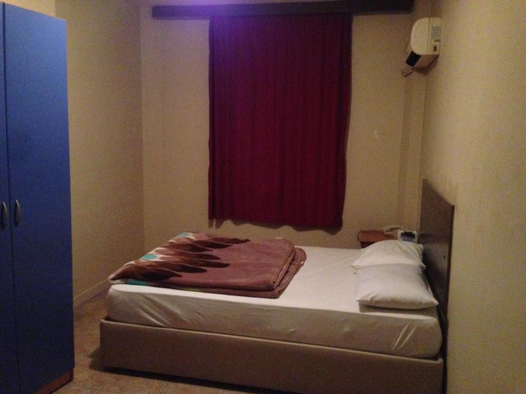 a bed in a room with a red window at Hotel Beyhan in Mersin