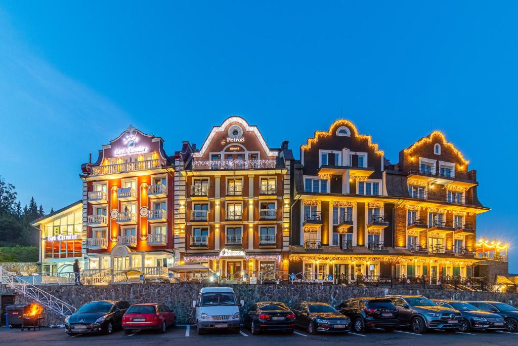 ein großes Gebäude, vor dem Autos parken in der Unterkunft Petros Hotel in Bukowel