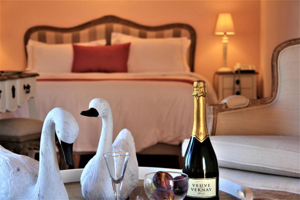 モネンバシアにあるLiotrivi Historical Mansion and Boutique Hotelの白鳥2頭がテーブルの上に座ってワインを1本