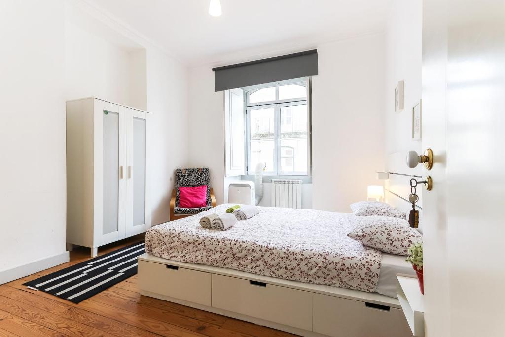 a white bedroom with a bed and a chair at Lisbon Silver Flower - Flat in Lisbon center in Lisbon