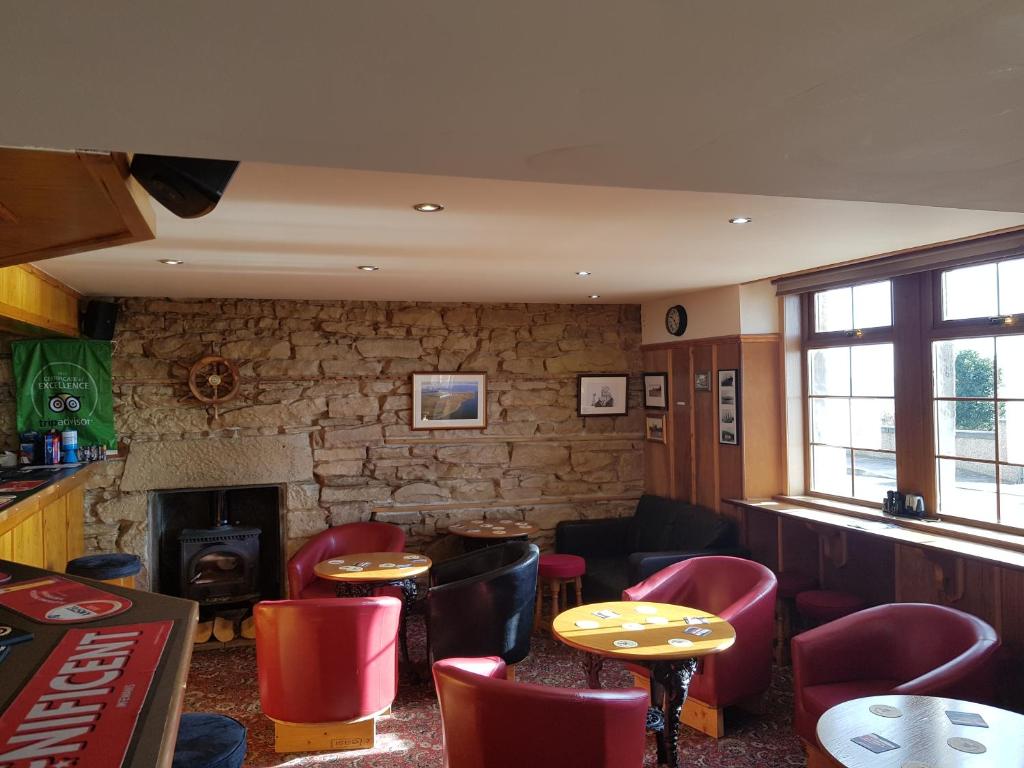 a restaurant with tables and chairs and a fireplace at Balintore Inn in Balintore