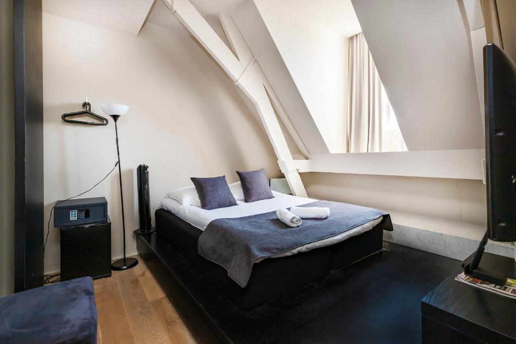 a bedroom with a bed with blue pillows and a window at AmsterHome Hotel in Amsterdam