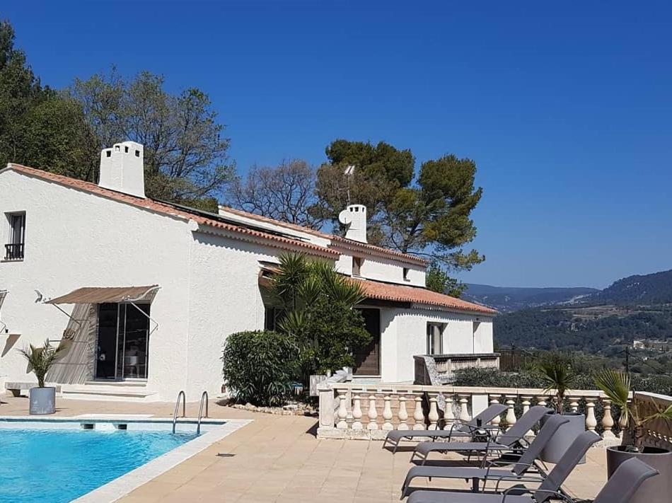 a house with a swimming pool and chairs next to it at Villa Manoe in Draguignan