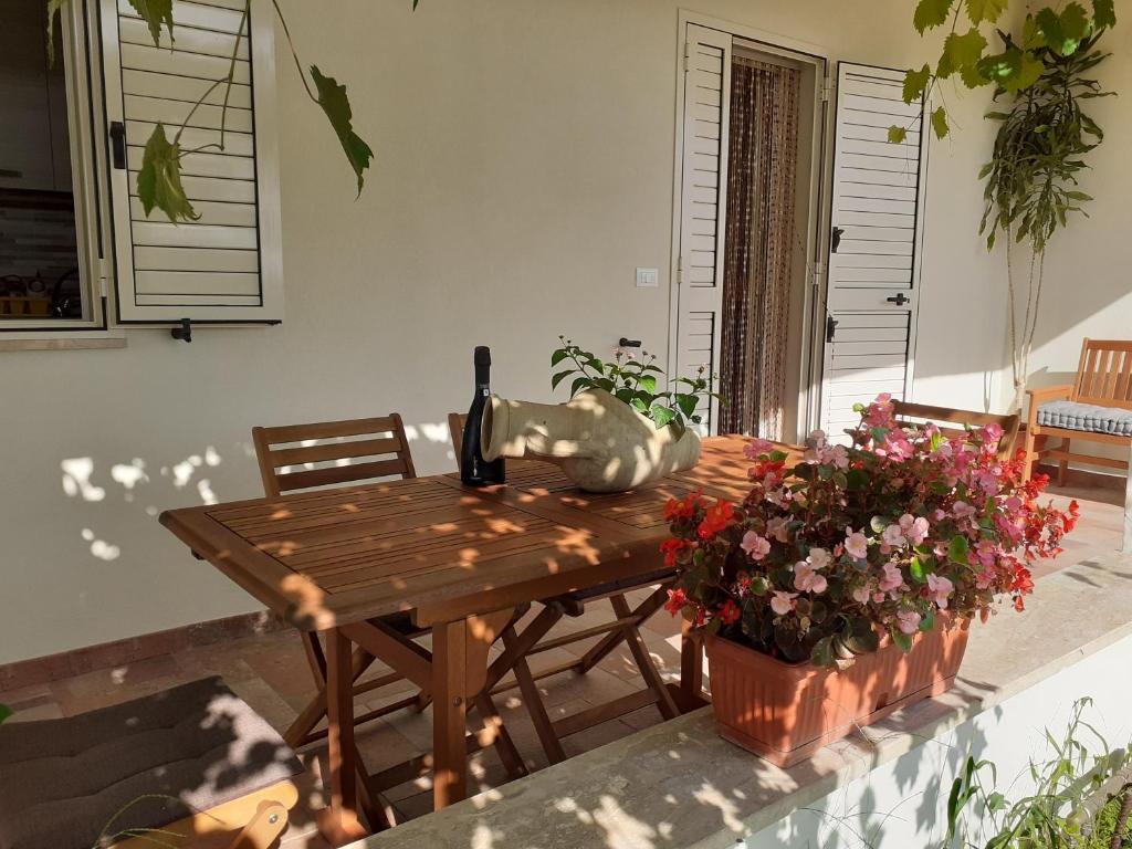 un tavolo in legno con una bottiglia di vino e fiori di Villa Pusortu a Orosei