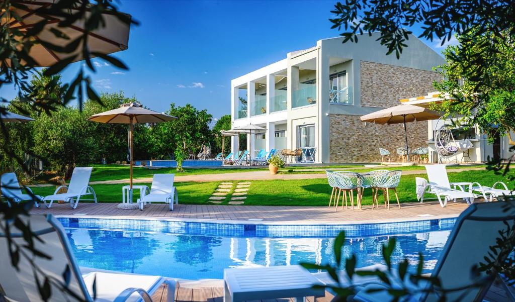 a house with a swimming pool with chairs and umbrellas at Alonaki Resort in Preveza