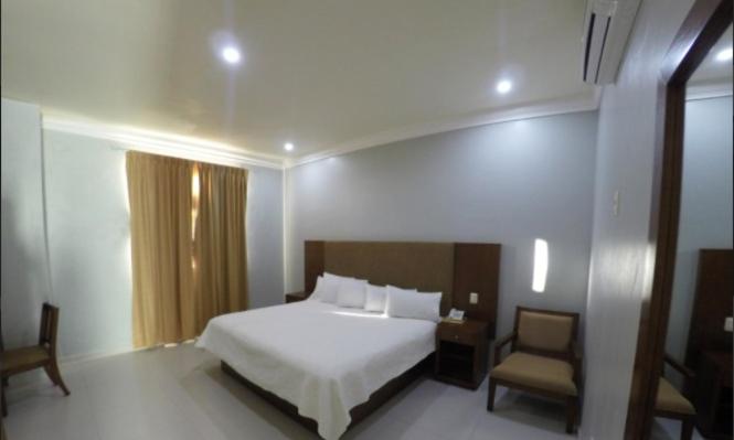 1 dormitorio con 1 cama blanca y 1 silla en Hotel Villa Montes, en Ezequiel Montes