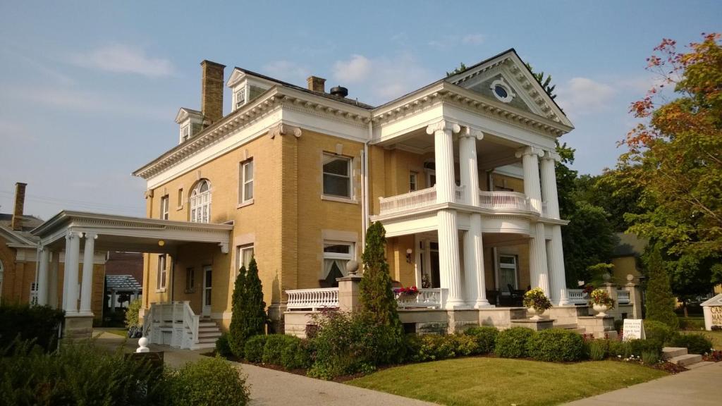 una gran casa amarilla con columnas blancas en Cartier Mansion, en Ludington