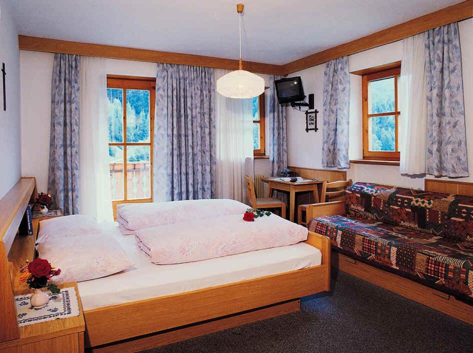 a small bedroom with a bed and a couch at Gasthof Mittermühl in Funes