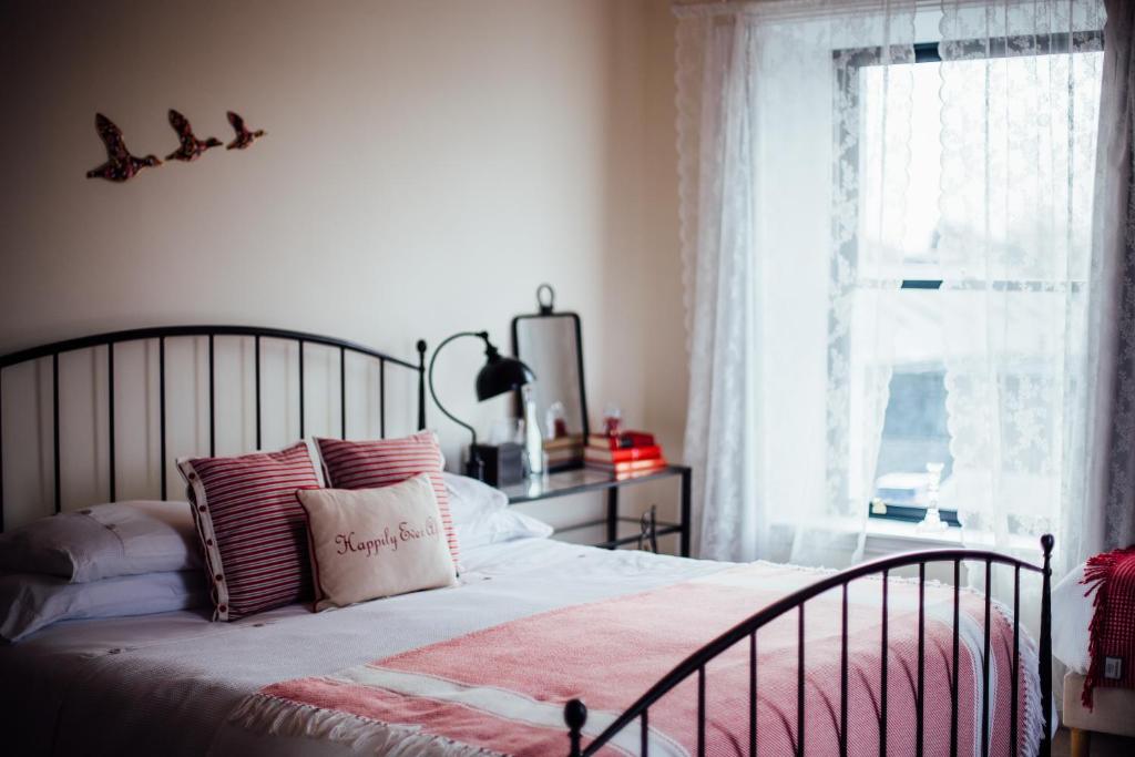 a bedroom with a bed with pink pillows and a window at Tom Blake House in Kells