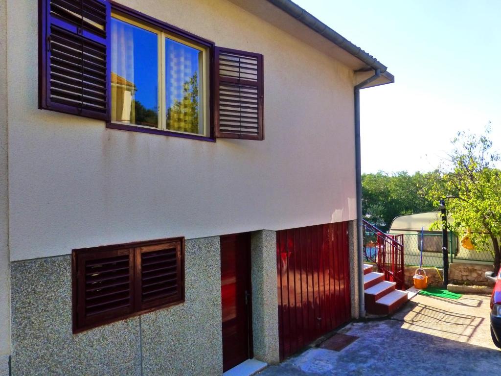 dom z dwoma oknami i czerwonymi drzwiami w obiekcie Apartment Zorić Grebaštica w mieście Grebaštica