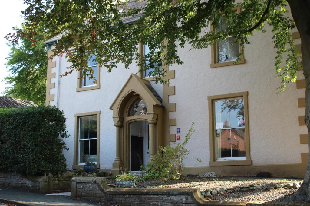 a white house with a tree in front of it at Bank House B and B in Penrith