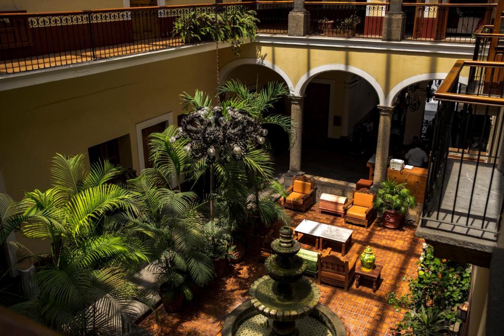 einen Innenhof mit Palmen und Stühlen in einem Gebäude in der Unterkunft Hotel San Francisco Plaza in Guadalajara