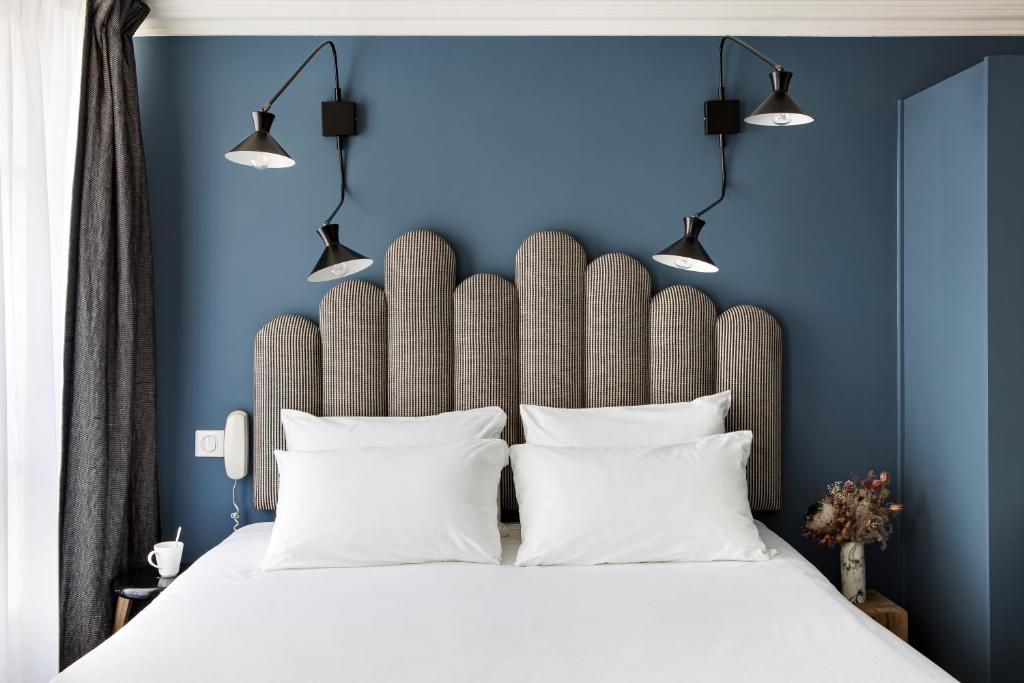 a bedroom with blue walls and a bed with white pillows at Hotel Paradis in Paris