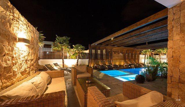 a patio with chairs and a swimming pool at night at Espacio Botavara in San José