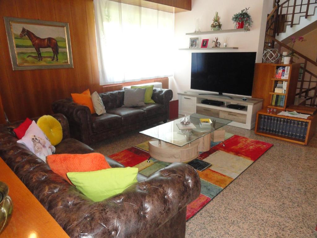 sala de estar con sofá de cuero y TV en HOUSE DOLCEVITA 30 min per Venezia, en Padua
