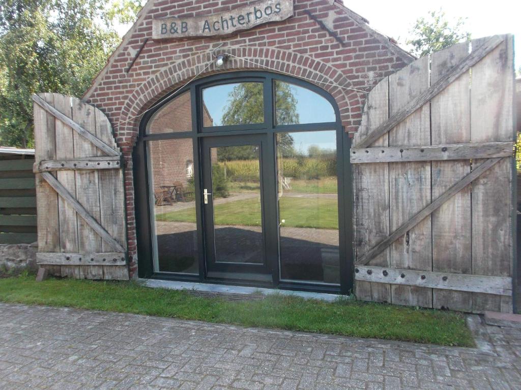 um edifício de tijolos com uma grande porta de vidro em Holiday Home Achterbos em Sint-Oedenrode