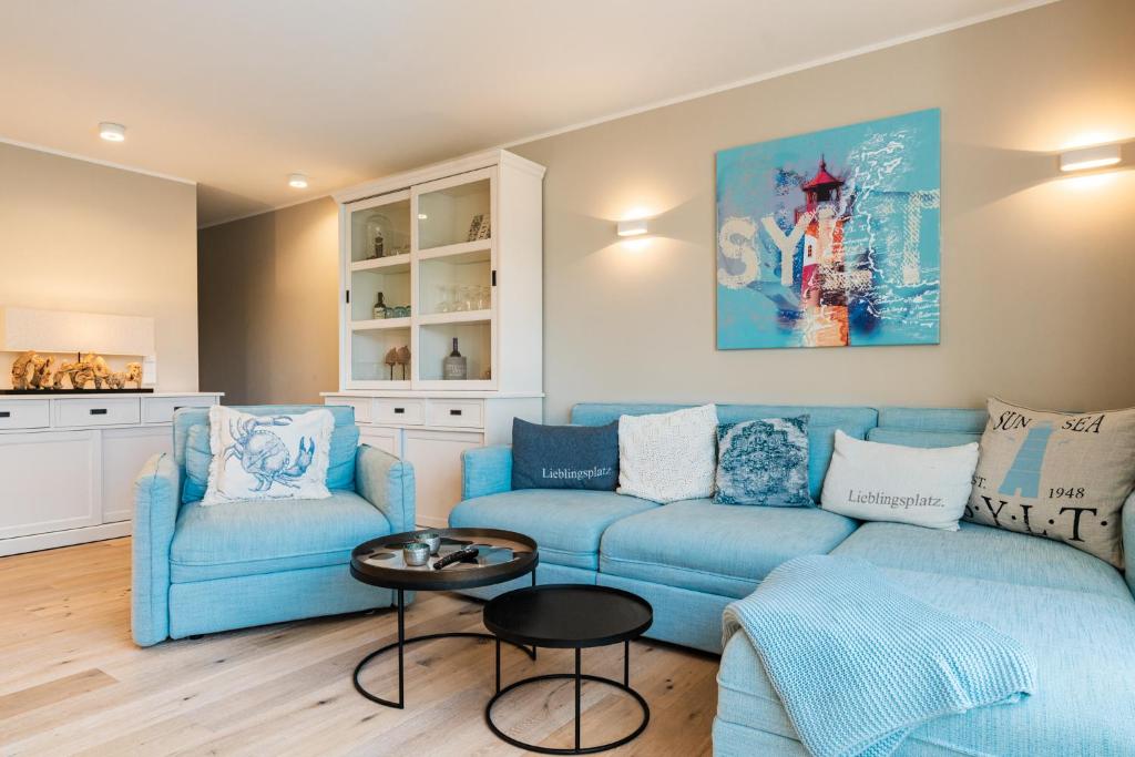 - un salon avec un canapé bleu et des chaises dans l'établissement Lieblingsplatz@K1-Sylt, à Westerland
