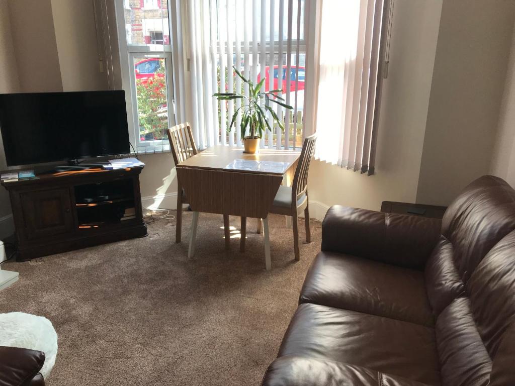 a living room with a table and a leather couch at Richmond Luxury flat Fabulous location in Southend-on-Sea