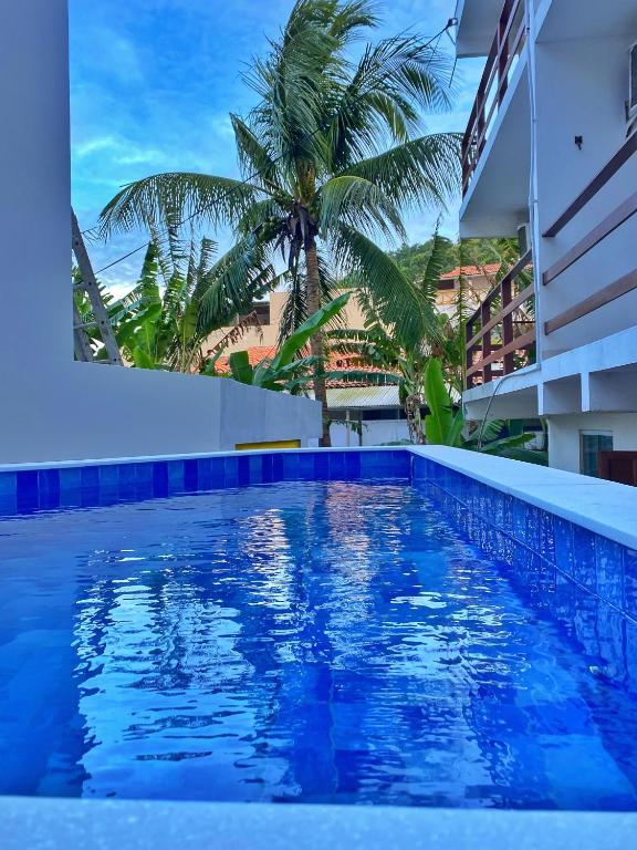 a swimming pool with a palm tree and a building at Pousada Primeira Praia Suítes in Morro de São Paulo