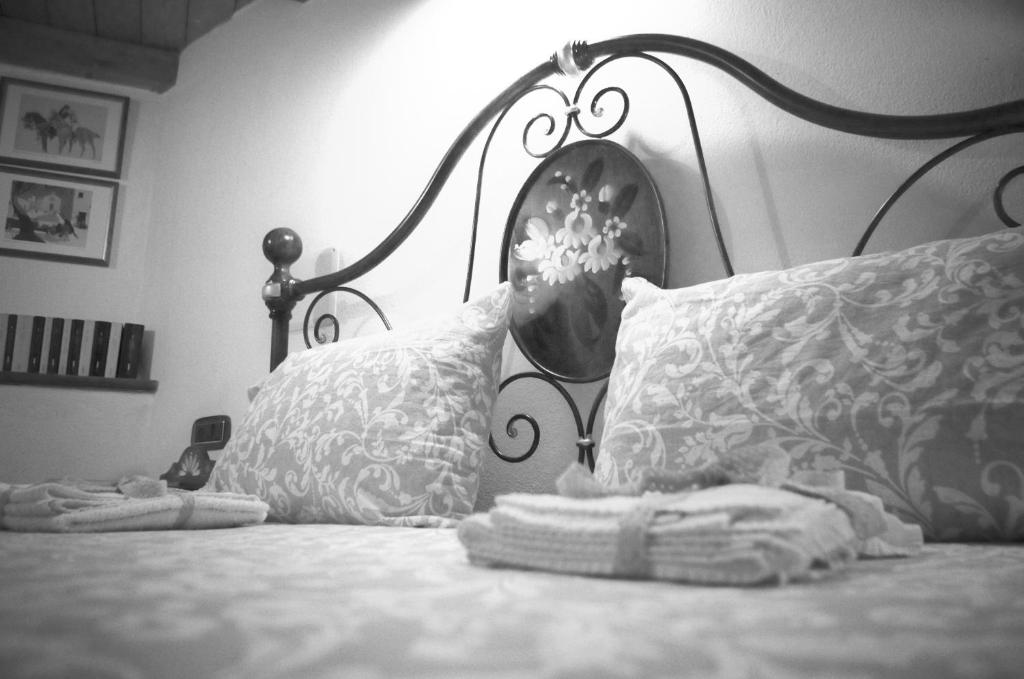 ein schwarz-weißes Foto eines Bettes mit Kissen in der Unterkunft Dè Ajala - B&B de Charme in Làconi