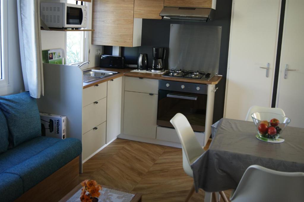 een kleine keuken met een tafel en een blauwe bank bij Mobil home neuf 3 chambres 8 personnes Fréjus in Fréjus