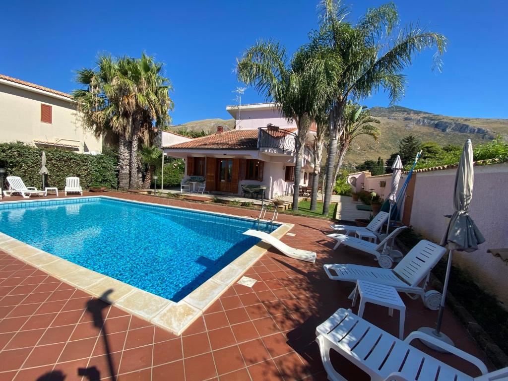 a swimming pool with chairs and a house at Villa Paloma in Castellammare del Golfo