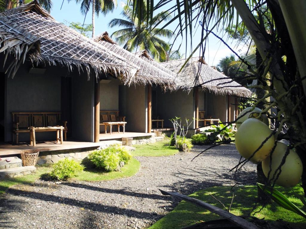 a house with a straw roof and a courtyard at Bale Karang Cottages in Batukaras