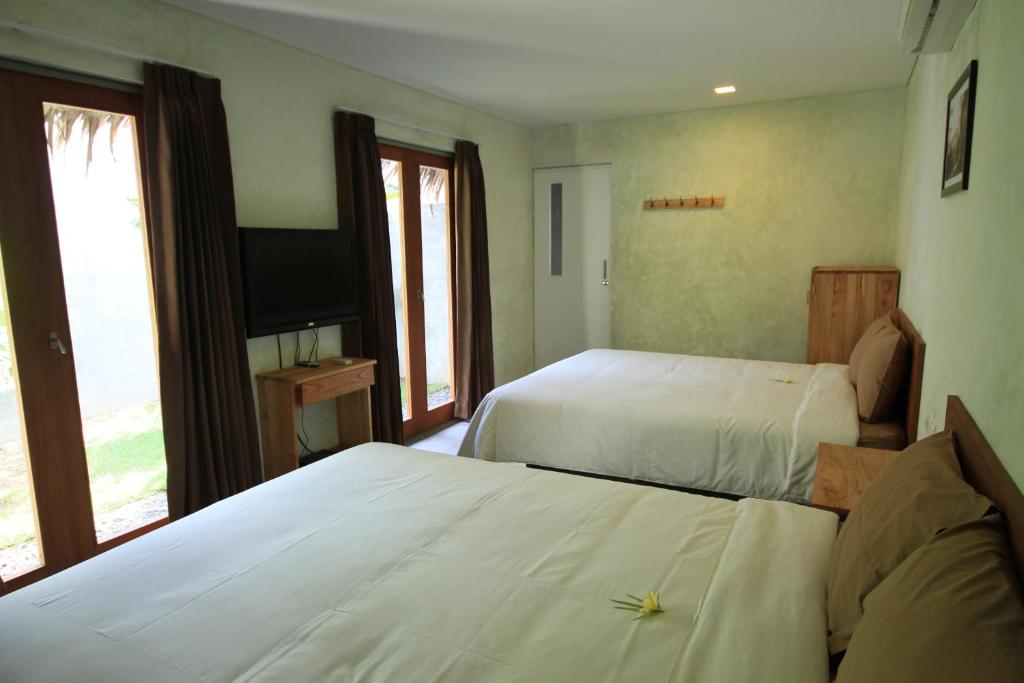 ein Hotelzimmer mit zwei Betten und einem Fernseher in der Unterkunft Bale Karang Cottages in Batukaras