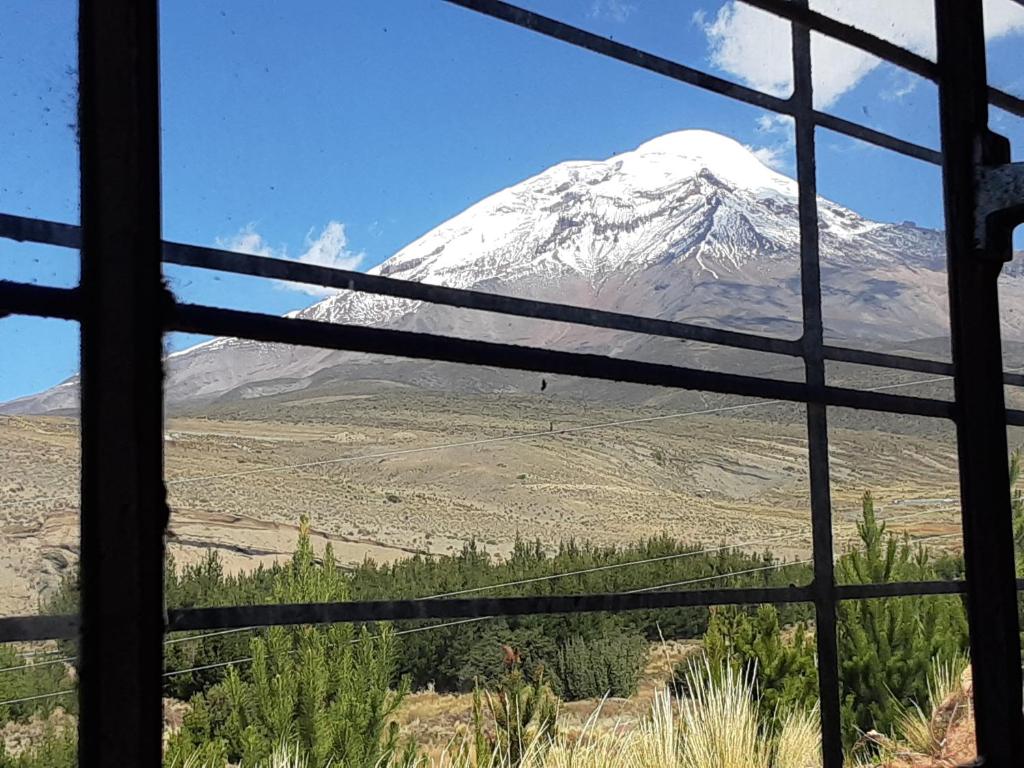 a view of a snow covered mountain through a window at Hospedaje Chimborazo in Chimborazo